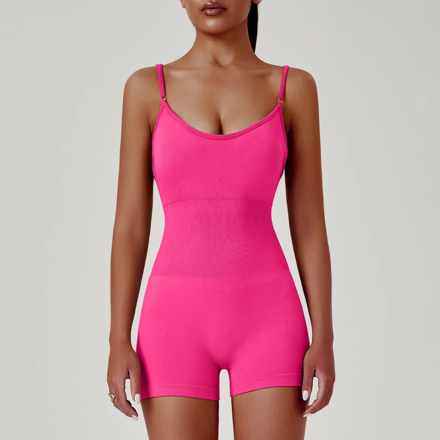 Person wearing a bright pink bodysuit against a plain background